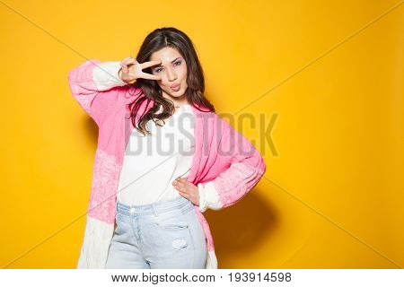 the girl in the pink jacket shows two fingers on a yellow background