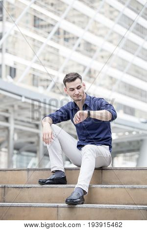 Young Handsome Businessman Looking To Wacth While Sitting At City. Woman Working At City Concept 20-