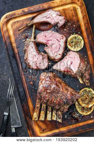 Barbecue Leg of Lamb and Rack as top view on burnt cutting board 