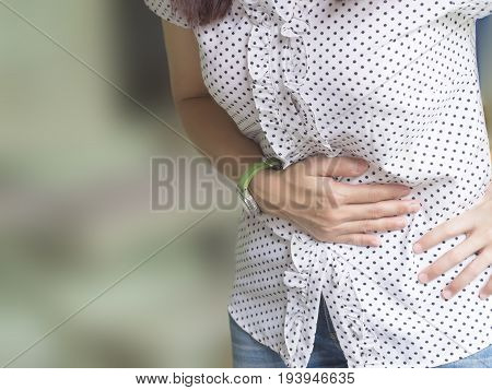 Woman holding her stomach. She is having a menstruation pain. Human suffering from stomachache pain. Person having period bellyache. Health.
