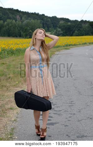 Alone young woman with violin case by country road