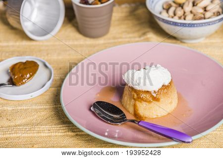Flan - A Sweet Custard Creme Caramel With Creme On Top, On A Pink Plate Over A Wooden Board.