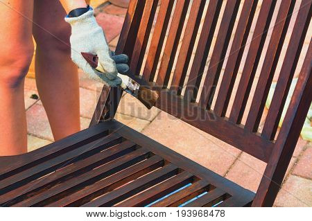 Painting and applying protective varnish on a wooden garden chair