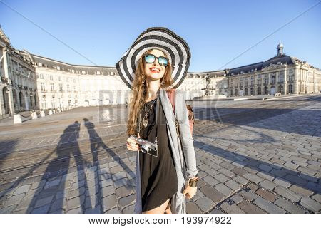Lifestyle portrait of a woman tourist walking with photocamera on the famous de la Bourse square in Bordeaux city in France