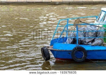 Boat to picking up trash from water on the river.