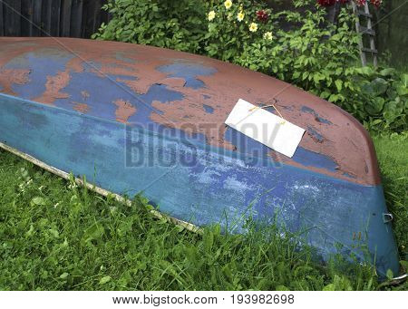 Capsized wooden boat with attached blank paper sheet for further design, outdoor cropped photo