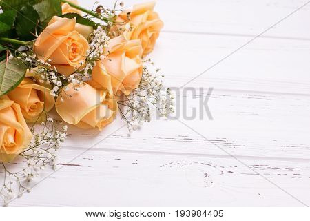 Fresh peach color roses flowers on white wooden background. Shubby chic. Place for text. Selective focus.