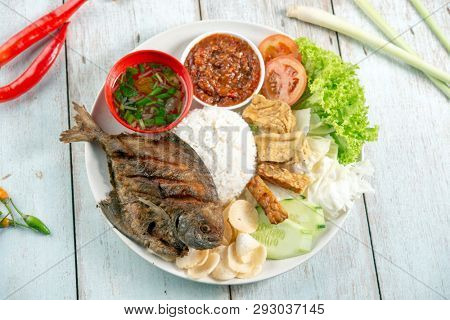 Fried pomfret fish and rice, popular traditional Malay or Indonesian local food. Flat lay top down overhead view.