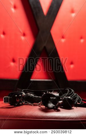 Sexy Black Leather Toys On Red Sofa.