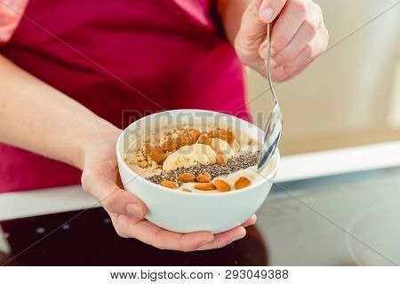 Close-up of woman's hand holding bowl of delicious oatmeal and spoon