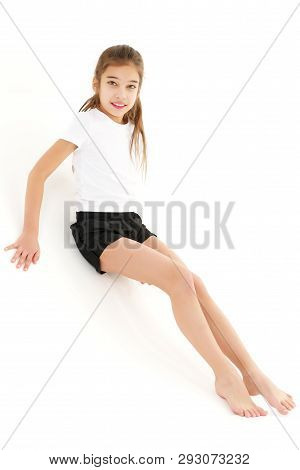 A Cute Little Girl Leaned Against A White Wall. Cyclorama In Studio. Isolated On A White Background.