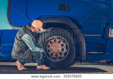 Caucasian Driver Checking Semi Truck Wheels Looking For Potential Issues. Transportation Industry Sa