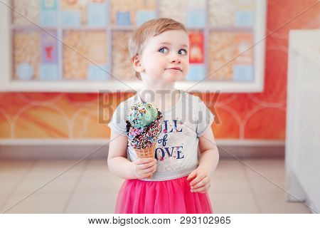 Cute Adorable Caucasian Blonde Toddler Girl Child With Blue Eyes Holding Ice Cream In Large Waffle C
