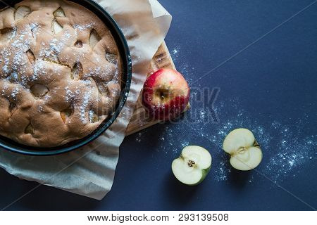 Apple Pie Covered With Sugar Pouder, Red Apple On The Wood Board And Two Halfs Of Green Apple On Dar