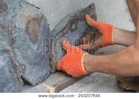 Glue The Stone On The Foundation, A Man Puts A Natural Stone On The Foundation Of The House