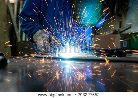 Welder in his workshop welding metal, lots of sparks flying around
