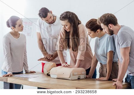 Group Of Concentrated People Performing Cpr On Dummy During First Aid Training
