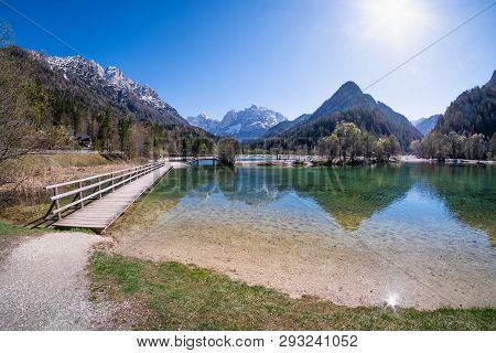 Bridge Over Lake Jasna With Mountains Razor And Prisojnik On The Horizont In Slovenia