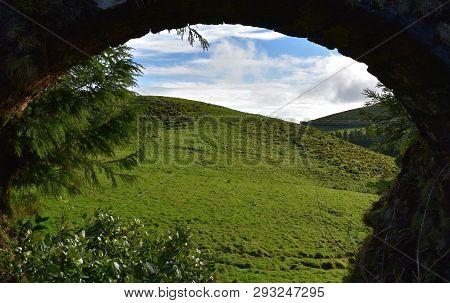 Attractive View Of A Green Field Visible Through A Aqueduct Archway.