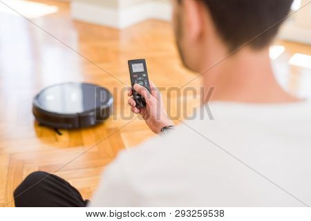 Close up of man hands controling automatic vacuum cleaner using electronic control of the mopping robot
