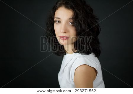 Portrait Of Female Face With Big Eyes And Short Curly Hair Looking At The Camera Instudio On Black B