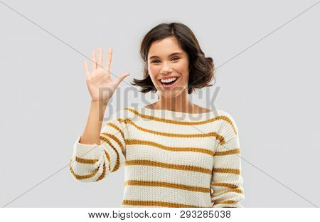 counting and people concept - happy smiling young woman in striped pullover showing five fingers of one hand over grey background
