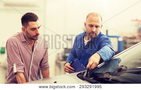 auto service, repair, maintenance and people concept - mechanic checking windshield wiper and man or owner at car shop