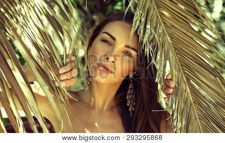 Beautiful Brunette Young Woman Between Palm Leaves