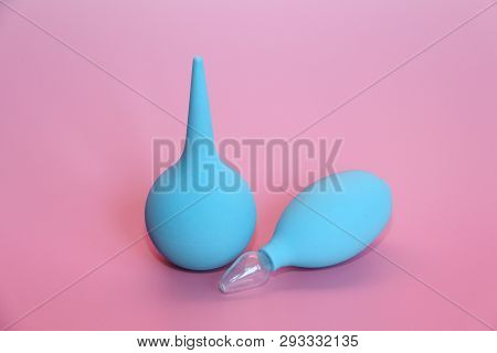 Blue Enema With A Soft Tip. Blue Nasal Aspirator With Glass Tip. Pink Background.
