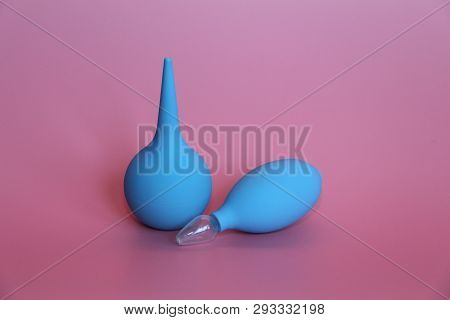 Blue Enema With A Soft Tip. Blue Nasal Aspirator With Glass Tip. Pink Background.