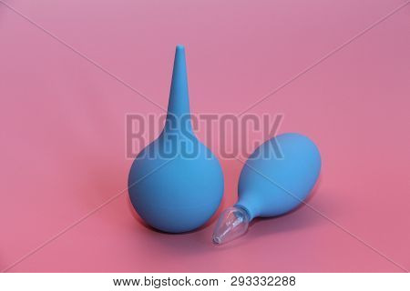 Blue Enema With A Soft Tip. Blue Nasal Aspirator With Glass Tip. Pink Background.