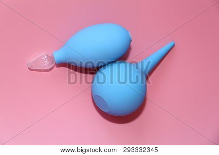 Blue Enema With A Soft Tip. Blue Nasal Aspirator With Glass Tip. Pink Background.