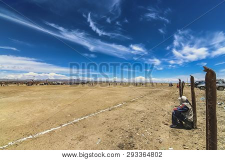 Colchani, Bolivia - Dec 2014: Spectators Watching Natives Play Football (soccer) In A Barren Field