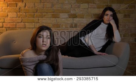 Closeup Portrait Of Two Young Pretty Girls Watching Tv With Fascinated Facial Expression While Resti