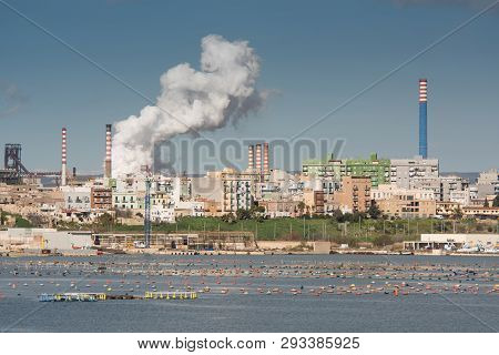 White Smoke Going Up From The Chimney Of Steel Plant Of  Taranto, Puglia. Italy