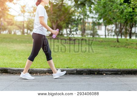 Woman Walking In The Park With Bottle Water In Summer.