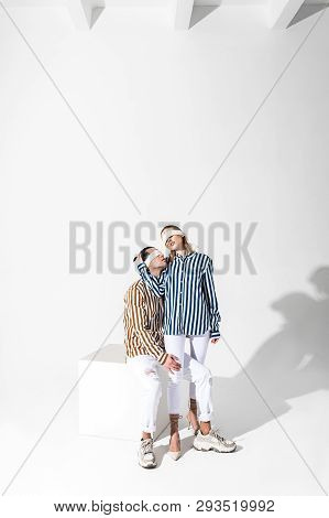 Blindfolded Couple Of Models Wearing White Trousers Posing Together