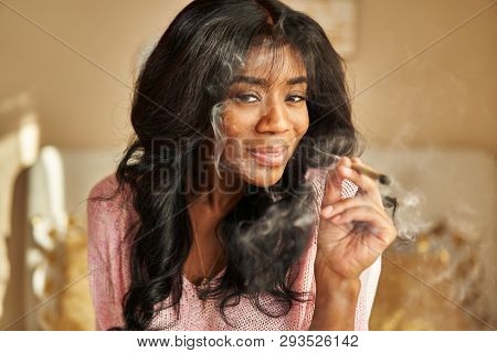 portrait of happy african american woman smoking pre-roll marijuana joint