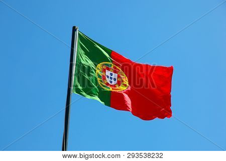 National Flag Of Portugal Blowing In The Wind On Flag Pole With Blue Sky Background. Portugal