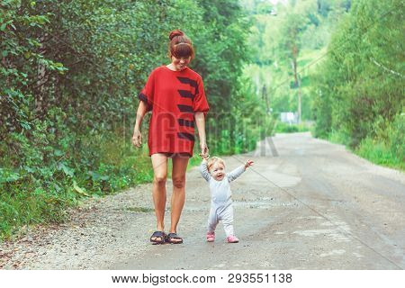 The Child Learns To Walk In The Park Barefoot On The Grass