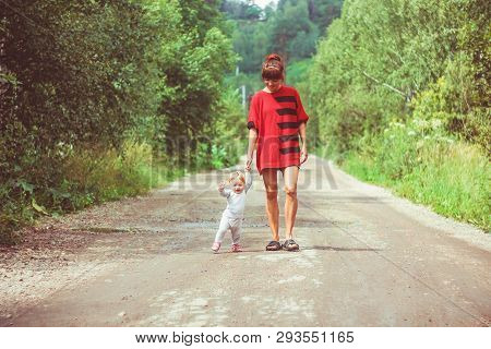 The Child Learns To Walk In The Park Barefoot On The Grass