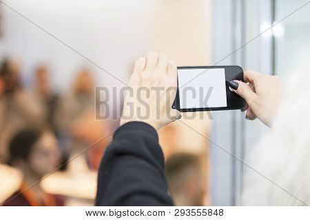 Hands Holding Smartphone With Empty Screen En Against Blurred People Background.