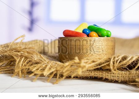 Lot Of Whole Sweet Licorice Comfit On Jute Cloth In A Wooden Bowl With Blue Window In Background