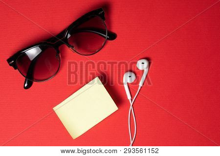 Smartphone With Blank Screen Connects To Earphones With Spiral Cable On Red Background Top View, Sun