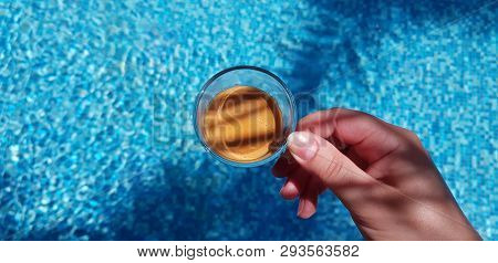 Small Coffee Cup In Female Hand Over Blue Waters In The Pool