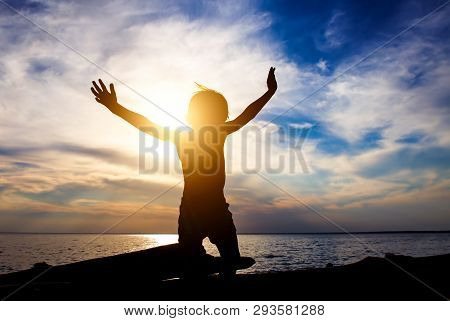 Happy Child Silhouette With Hands Up On The Sunset Background