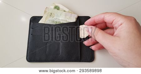 Black Wallet With One Yuan Banknote In It While Female Hand Takes Out Two Hong Kong Dollars Coin