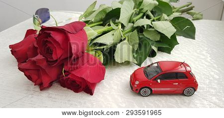 Rishon Lezion, Israel - March 8 2019: Small Red Fiat 500 Toy On White Table Near Five Roses Bouquet 