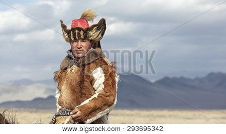 Kazakh Eagle Hunter Traveling On Hgis Hotse In A Landscape Of Altai Mountains