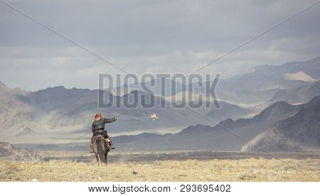 Kazakh Eagle Hunter Traveling On Hgis Hotse In A Landscape Of Altai Mountains